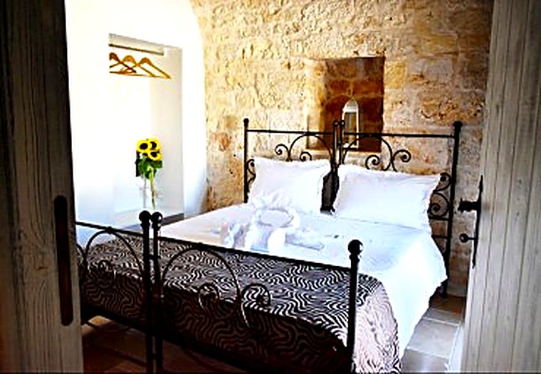 Camera da letto nel trullo, con pareti in pietra